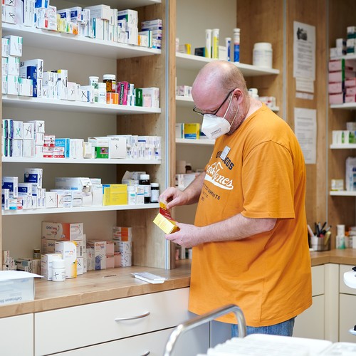 Ein Mann steht in einem Medikamentenraum und sortiert Medizin