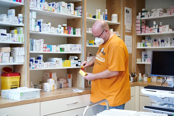 Mann steht in einem Medikamentenraum und sortiert Medizin